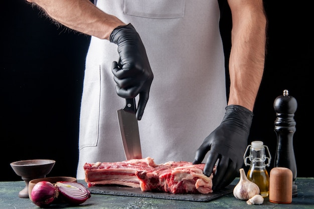 Vooraanzicht mannelijke slager die vlees op donkere oppervlakte snijdt