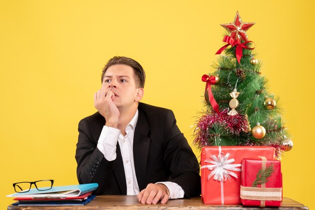 Vooraanzicht mannelijke werknemer in pak zit achter zijn werktafel stressfullu denken