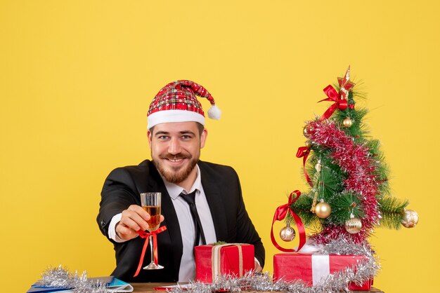 Vooraanzicht mannelijke werknemer Kerstmis vieren met champagne op geel