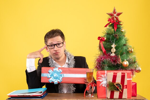 Vooraanzicht mannelijke werknemer zitten en houden kerstcadeau