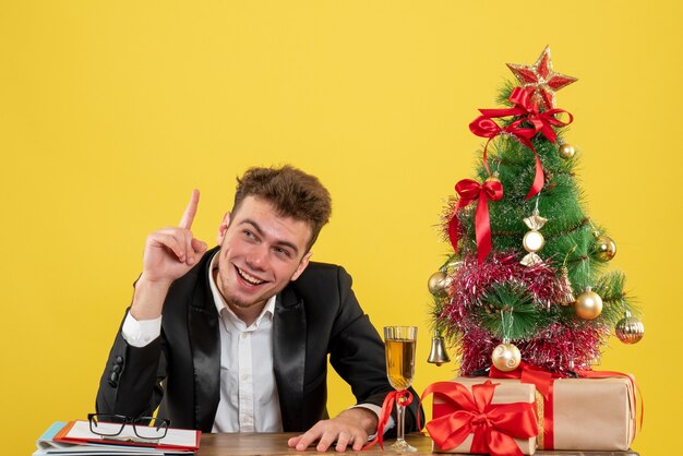 Vooraanzicht mannelijke werknemer zittend achter zijn werkplek op een geel