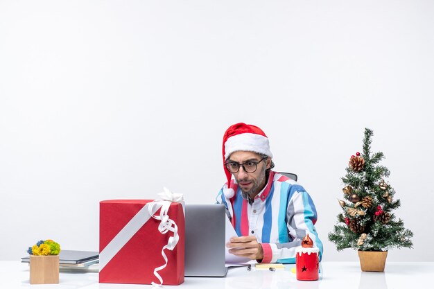Vooraanzicht mannelijke werknemer zittend op zijn plaats met laptop die werkt met documenten kantoor emotie baan xmas