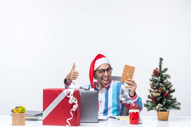 Vooraanzicht mannelijke werknemer zittend op zijn werkplek met pakket vakantie emotie baan kerst kantoor