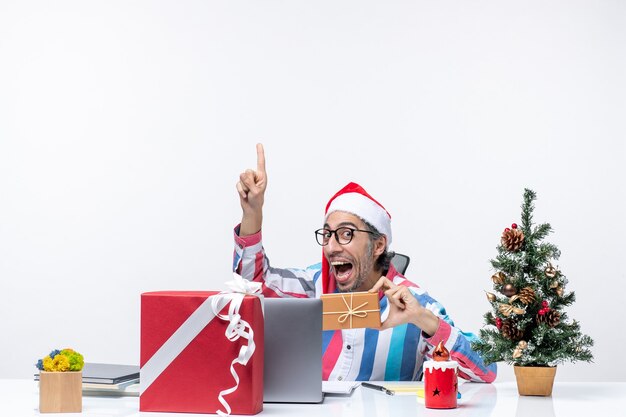 Vooraanzicht mannelijke werknemer zittend op zijn werkplek met pakketvakanties emotie kerst baan kantoor