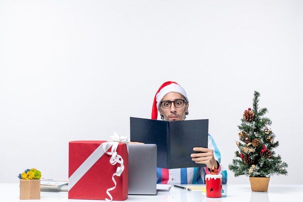 Vooraanzicht mannelijke werknemer zittend op zijn werkplek met voorbeeldenboek