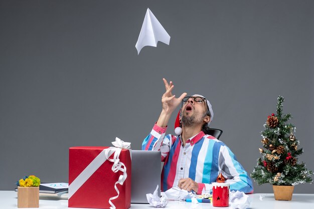 Vooraanzicht mannelijke werknemer zittend op zijn werkplek spelen met papieren vliegtuigje