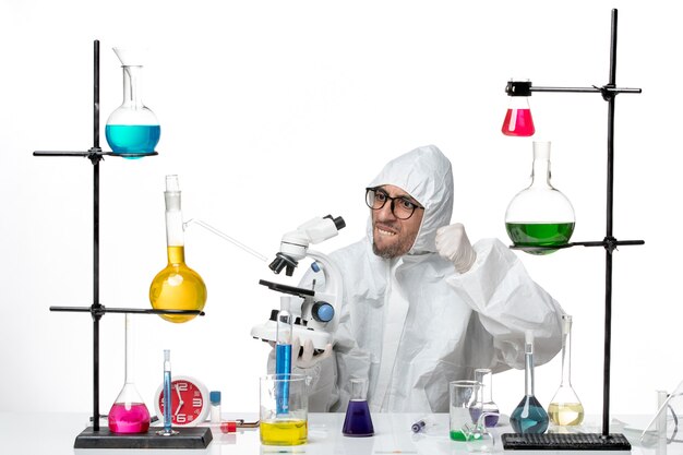 Vooraanzicht mannelijke wetenschapper in speciale beschermende pak met microscoop