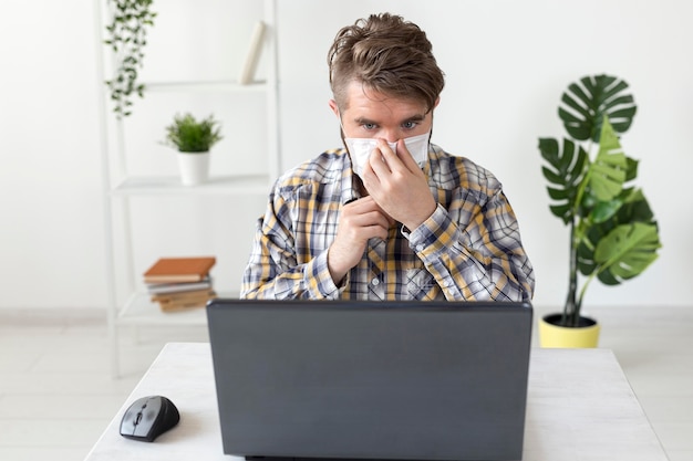 Gratis foto vooraanzicht mannetje met gezichtsmasker thuis werken