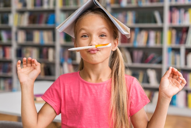 Gratis foto vooraanzicht meisje dat dwaas in de bibliotheek