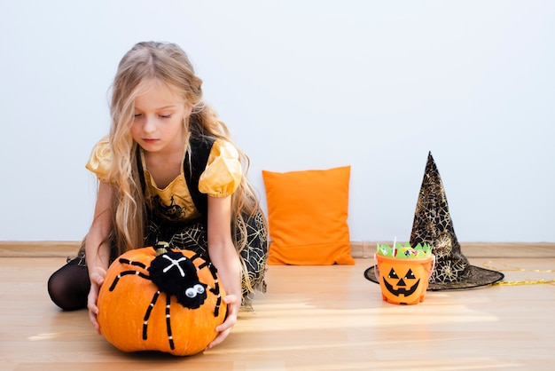 Vooraanzicht meisje, zittend op de vloer op halloween