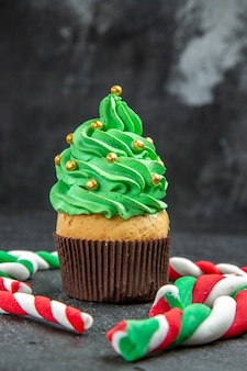 Vooraanzicht mini kerstboom cupcake en kerst snoepjes op donkere achtergrond