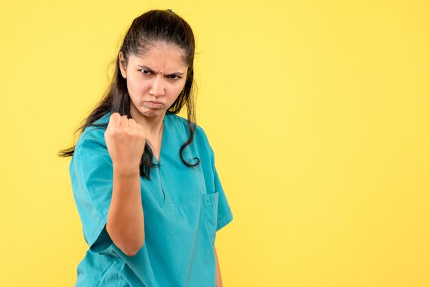 Vooraanzicht ontevreden vrouwelijke arts in uniform staande op gele geïsoleerde achtergrond
