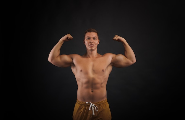 Vooraanzicht op getrainde bodybuilder torso. Man toont biceps. Portret van opgepompte man op zwarte achtergrond. Relief lichaam concept.