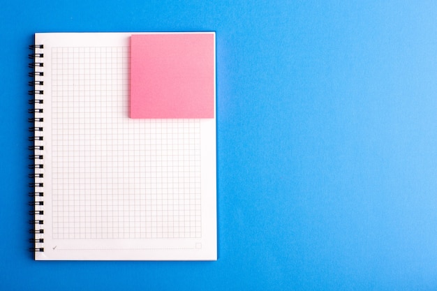 Vooraanzicht open voorbeeldenboek met roze sticker op het blauwe bureau