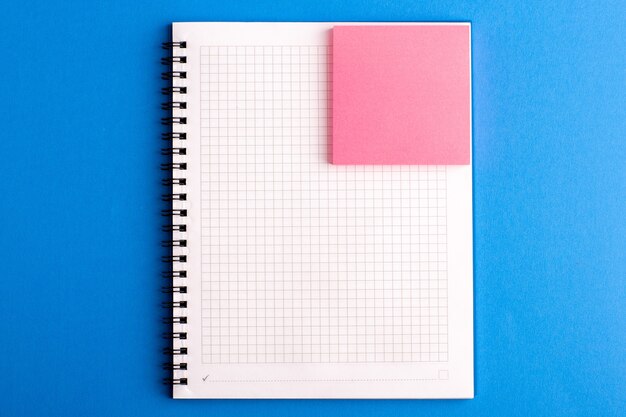 Vooraanzicht open voorbeeldenboek met roze sticker op het blauwe bureau