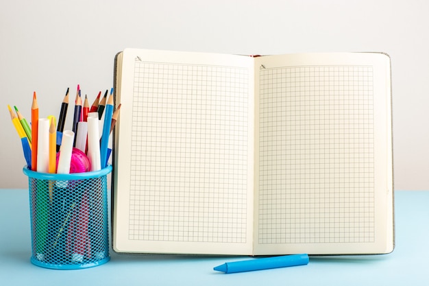 Vooraanzicht open voorbeeldenboek met viltstiften en potloden op blauw bureau