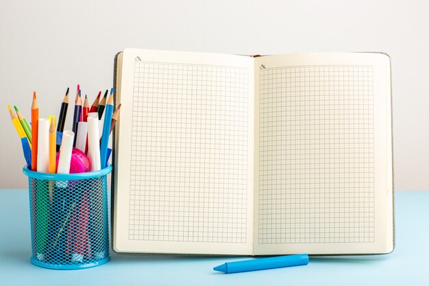 Vooraanzicht open voorbeeldenboek met viltstiften en potloden op blauw bureau