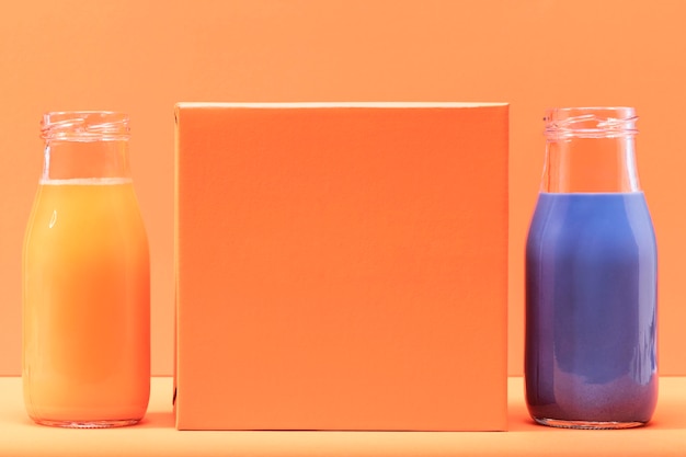 Gratis foto vooraanzicht oranje en blauwe smoothies met blanco oranje vierkant