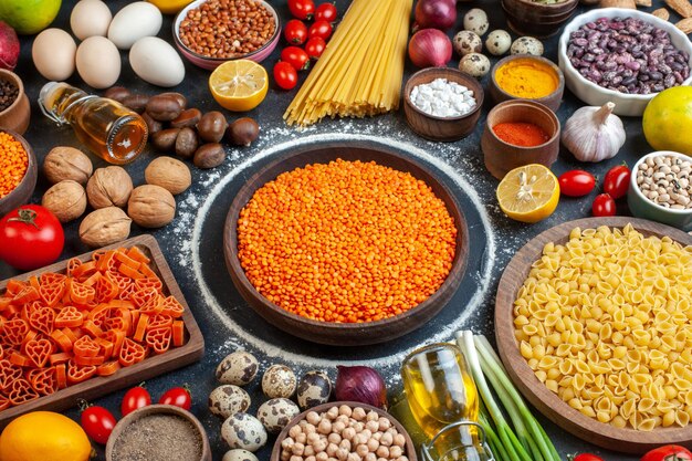 Vooraanzicht oranje linzen met noten eieren groenten rauwe pasta en kruiderijen op donkergrijze achtergrond rauwe maaltijd dieet keuken kleur foto notenboon