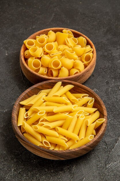 Vooraanzicht pasta samenstelling rauwe producten binnen platen op grijze ruimte
