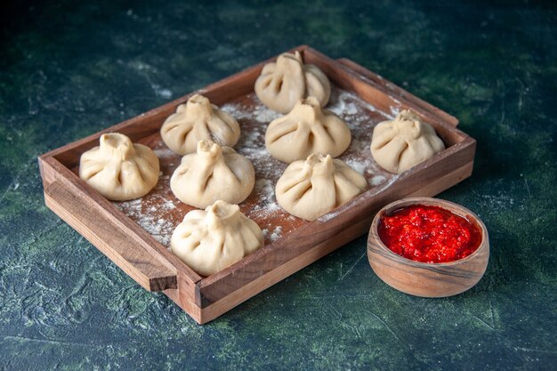 Vooraanzicht rauwe dumplings met vlees binnen op donkere ondergrond schotel kleur maaltijd meel koken peper deeg vlees