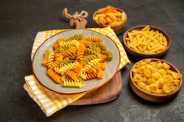 Vooraanzicht rauwe Italiaanse pasta anders gevormd in bruine platen op grijze ruimte