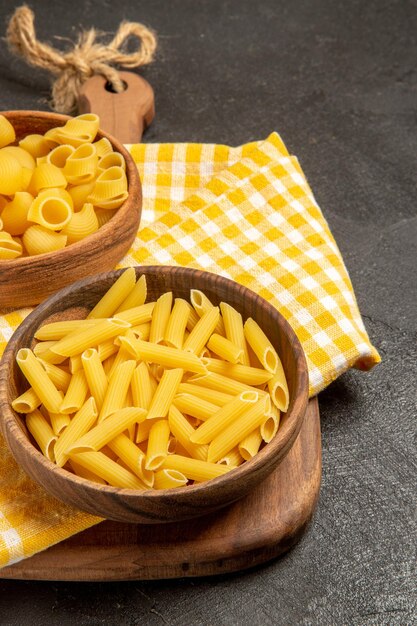 Vooraanzicht rauwe Italiaanse pasta in bruine borden op grijze ruimte
