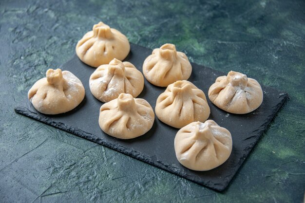 Vooraanzicht rauwe kleine dumplings met vlees binnen op donkere ondergrond kleur schotel rauw koken maaltijd deeg vleesmeel