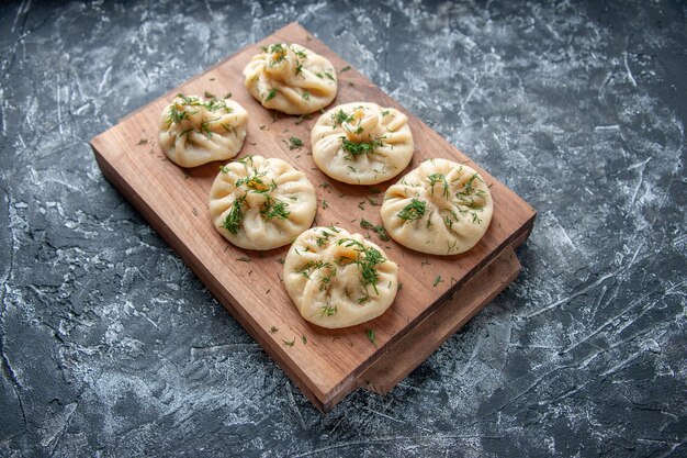 Vooraanzicht rauwe kleine knoedels met greens en vlees binnen op grijze oppervlak deeg taart hotcake koken keuken maaltijd cake