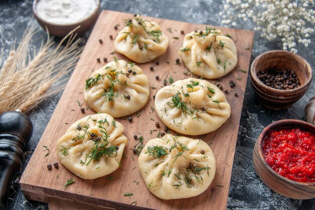 Vooraanzicht rauwe kleine knoedels met tomatensaus en kruiden op grijs tafel vlees deeg maaltijd koken schotel keuken diner