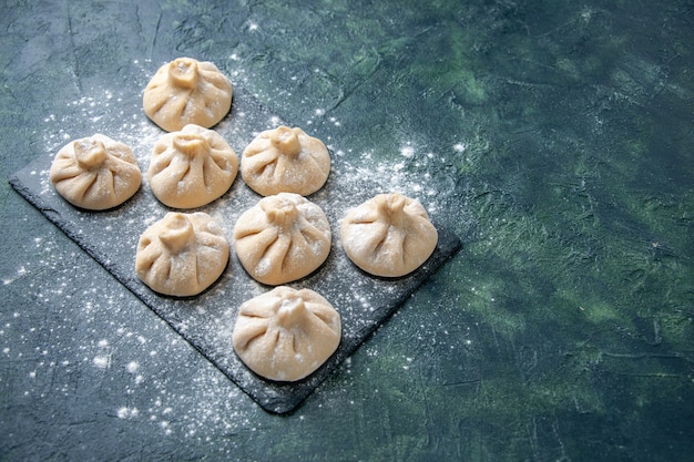 Vooraanzicht rauwe kleine knoedels met vlees binnen op donkere achtergrond kleur schotel rauw koken maaltijd keuken deeg vlees meel