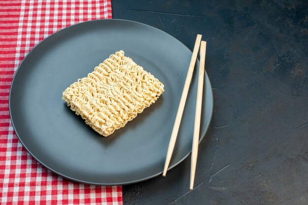 Vooraanzicht rauwe noedels in plaat met stokken op donkere tafel