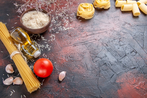 Gratis foto vooraanzicht rauwe pasta met verschillende ingrediënten op donkere oppervlak deeg pasta rauw