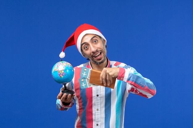Vooraanzicht regelmatige man met kaartjes en globe op blauwe muur kleur vakantie nieuwjaar