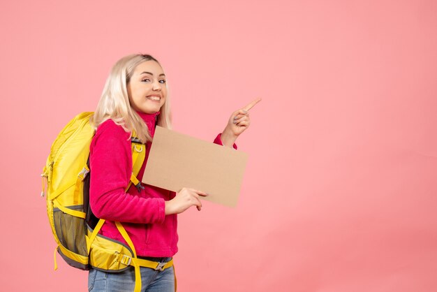 Vooraanzicht reiziger vrouw met rugzak met karton wijzend naar rechts