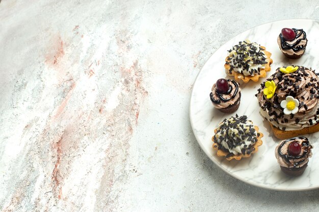 Vooraanzicht romige heerlijke taarten met chocolade cips op witte oppervlakte cake biscuit cookie thee zoete room