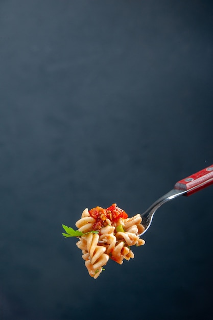Vooraanzicht rotini pasta op vork op donkere geïsoleerde oppervlak met vrije ruimte