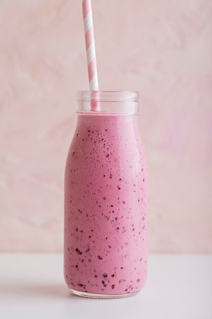 Gratis foto vooraanzicht roze smoothiefles met stro