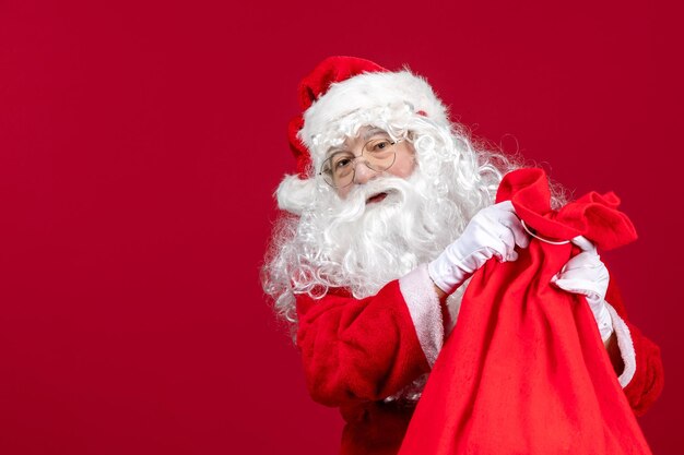 Vooraanzicht santa claus opening zak vol cadeautjes voor kinderen op rode vakantie kerstemotie