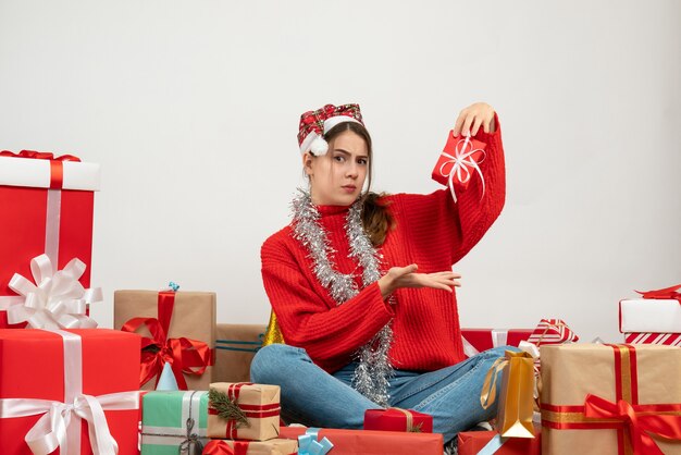 Vooraanzicht schattig feestmeisje met kerstmuts bedrijf aanwezig rondhangen cadeautjes