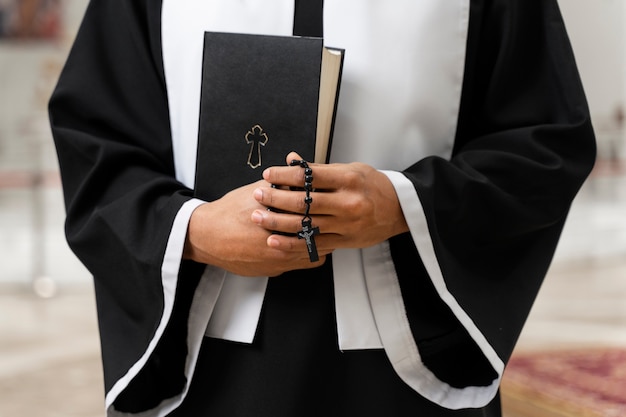 Vooraanzicht senior priester bij kerk met bijbel