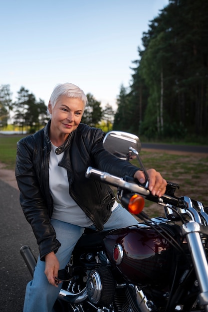 Gratis foto vooraanzicht senior vrouw met motorfiets