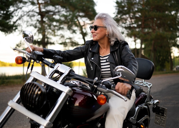 Gratis foto vooraanzicht senior vrouw met motorfiets