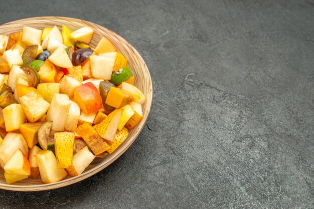 Vooraanzicht smakelijke fruitsalade bestaat uit vers fruit op de grijze tafel veel vers fruit