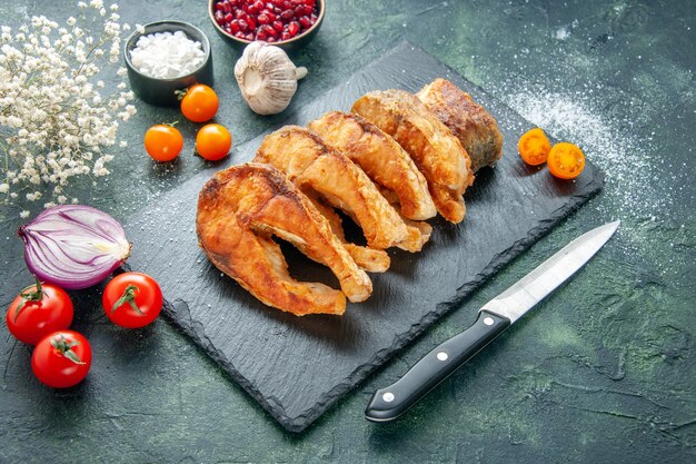 Vooraanzicht smakelijke gebakken vis met tomaten op donkerblauwe oppervlakte maaltijd peper kookgerecht bak zeevruchten zeevruchten zeevruchtensalade