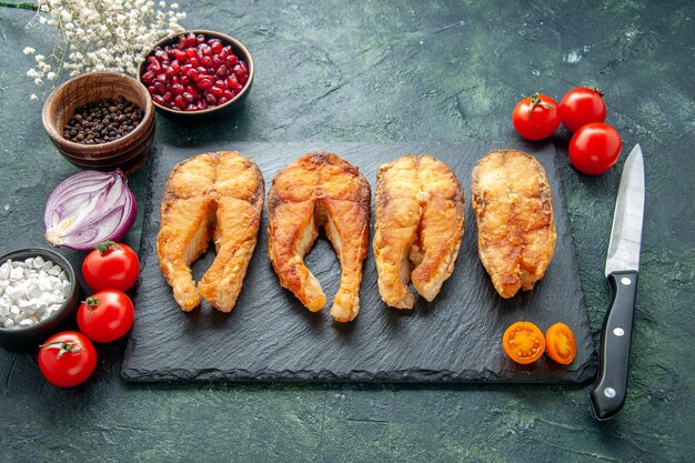 Vooraanzicht smakelijke gebakken vis met tomaten op donkere ondergrond koken schotel voedselsalade vlees gebraden zeemaaltijd zeevruchten peper