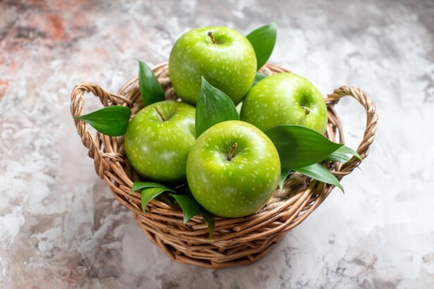Vooraanzicht smakelijke groene appels in mand op lichte achtergrond