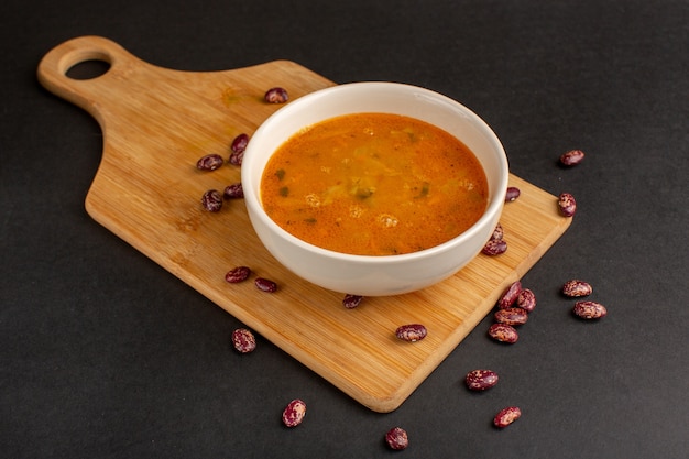 Gratis foto vooraanzicht smakelijke groentesoep in plaat samen met rauwe bonen op het donkere bureau.