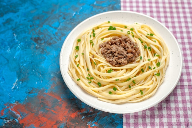 Vooraanzicht smakelijke italiaanse pasta met gehakt op blauwe kleur deeg schotel vlees maaltijd eten