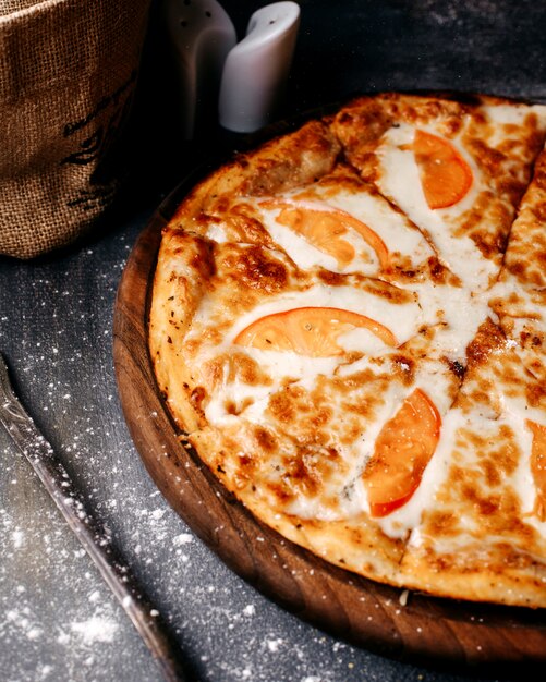 Vooraanzicht smakelijke pizza met rode tomaten en kaas op de grijze vloer